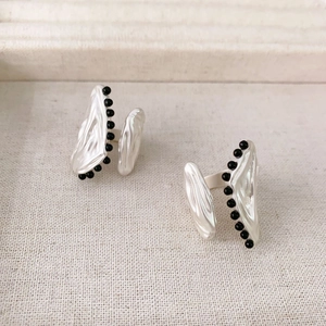 Artistic silver pleated lava texture open rings with black onyx beads on beige background