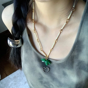 Detail of bamboo joint necklace with green elephant pendant on a model neck