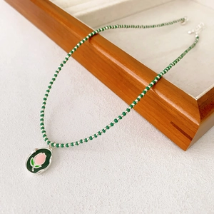 Collier de perles en agate verte avec pendentif tulipe émaillé sur plateau en bois