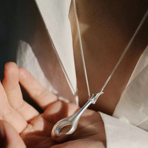 Minimalist silver perfume bottle pendant necklace with hollow drop design on model