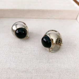 Symmetric silver earrings with black onyx hemispheres on textured background