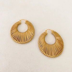 Detail of bohemian gold hoop earrings with ribbed fan texture and beaded edges