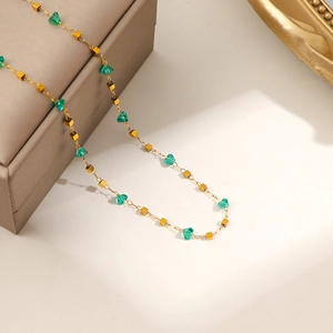 Elegante Halskette aus Goldtitan mit smaragdgrünen Kristallperlen auf weißem Hintergrund