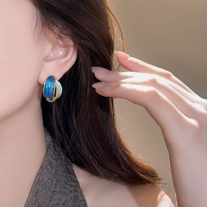 French vintage intertwined hoop earrings with blue enamel and gold finish on model