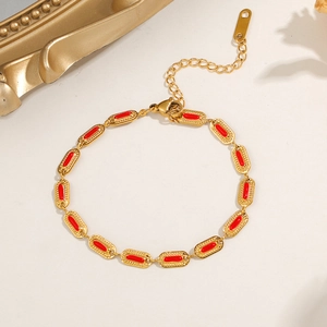 Detailed close-up of gold titanium steel bracelet with red oval enamel charms and clasp