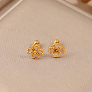 Boucles d'oreilles trèfle dorées avec cœurs en nacre blanche sur du velours