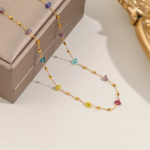 Collana in acciaio al titanio dorato con perline colorate su portagioie elegante