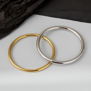 Polished 4mm stainless steel bangles in gold and silver finish set on a gray background