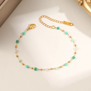 Golden beaded bracelet featuring green and white square crystals on a minimalist chain