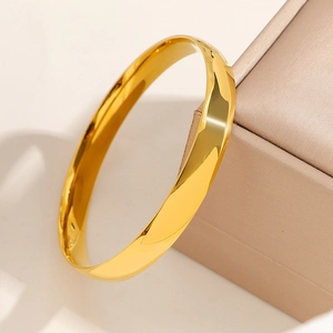 Polished 8mm gold stainless steel minimalist bangle on premium jewelry display