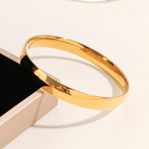 Minimalist 8mm wide polished gold stainless steel bangle bracelet in a luxury jewelry box