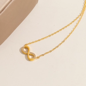 Macro detail of a gold infinity pendant necklace with sparkling pavé-set crystals