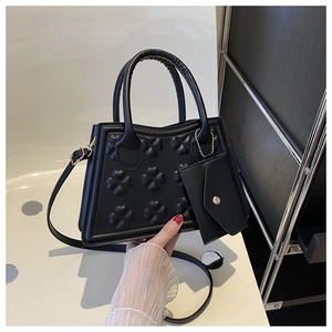 Detail van zwarte crossbodytas met klaverreliëf en afneembaar klein tasje met ketting
