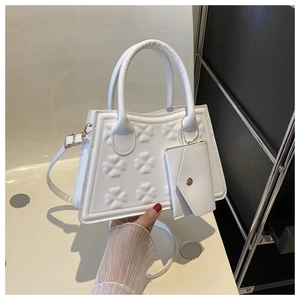 Detail van witte trapeziumtas met klaverreliëf en bijpassend mini-enveloptasje