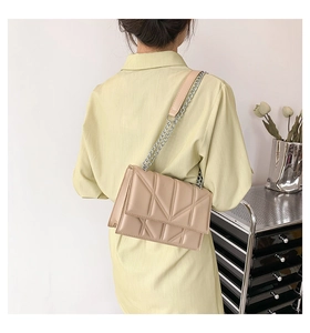 Model wearing a quilted cream shoulder bag with silver chain strap and PU leather finish