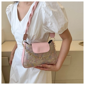 Detail einer rosa Vintage-Schultertasche mit Blumendruck und goldener Blütenkette