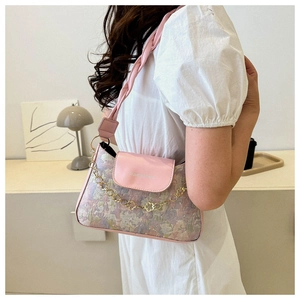 Detail der Vintage-Sticktasche mit goldener Blütenkette und rosa Schultergurt im Fokus