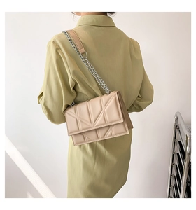 Detail of a beige quilted chain shoulder bag shown on a model for casual daily wear