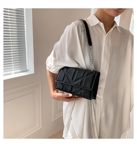 Detail shot of black crossbody bag with geometric triangle quilting and silver chain strap