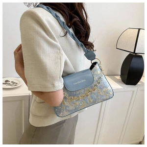 Blaue Bestickte Umhängetasche an Model mit Goldkette und Retro-Blumenmuster
