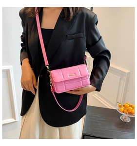 Detail van roze gewatteerde crossbodytas met gouden metalen staaf en kettingriem