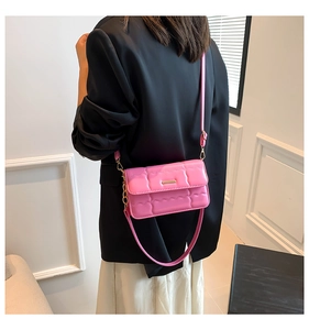 Detail van helderroze gewatteerde crossbodytas met goudkleurige details en schouderband