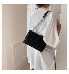Detail view of black quilted leather shoulder bag with silver chain strap on model