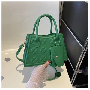 Detail van groene trapeziumtas met klaverreliëf en afneembaar mini-etui aan handvat