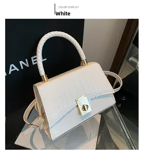 Detail of white crocodile embossed leather handbag with woven handle and gold twist lock