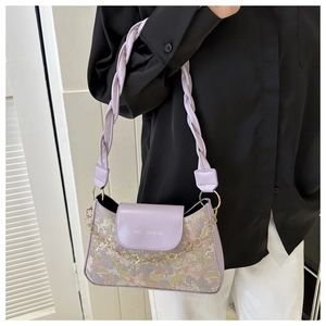 Detail der lila floralen Achseltasche mit goldener Blumenkette und Modetext
