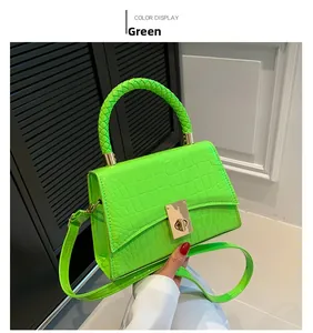 Detail of green crocodile texture handbag with woven handle and gold metal twist lock