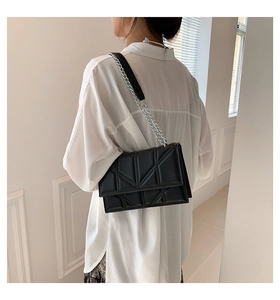 Close-up of black geometric quilted shoulder bag with silver metal chain strap