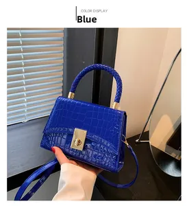 Close-up of blue crocodile pattern handbag with woven handle and gold twist lock