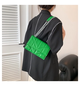 Detail of green crossbody bag with geometric triangle quilting and silver chain strap