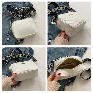 Detail of white camera bag with V-quilted texture and wide jacquard letter strap
