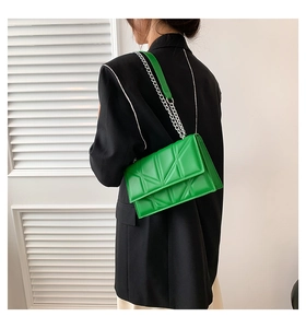 Green crossbody chain bag with geometric quilted pattern shown on black blazer