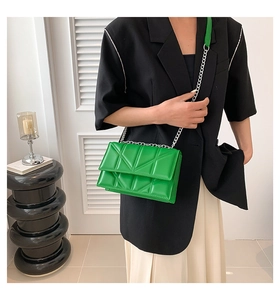 Fashionable green quilted crossbody bag with silver chain strap shown on model shoulder