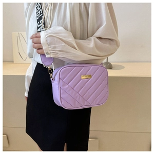 Detail of lavender quilted camera bag with wide letter-printed strap and metal logo