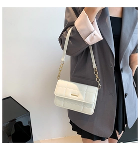 Detail van witte gewatteerde crossbodytas met gouden gesp en elegante kettingriem