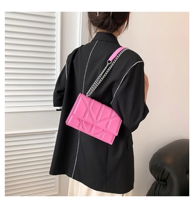 Detail of pink quilted shoulder bag featuring classic geometric pattern and chain strap
