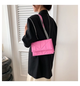 Pink quilted flap crossbody bag with silver chain strap worn by model over black blazer