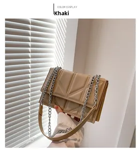 Detail of khaki square handbag featuring geometric quilting and silver chain strap