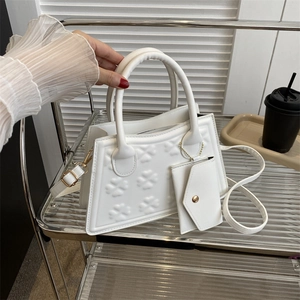 Witte trapeze handtas met klaver-reliëf en een bijpassende kleine portemonnee