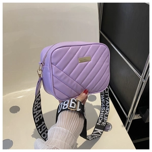 Close-up of lavender crossbody bag with diamond quilting and wide logo strap