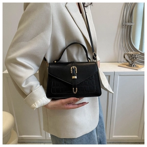 Fashionable black crocodile texture handbag with gold hardware shown on a model