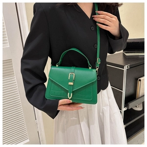 Detail of green crocodile embossed handbag with gold buckle and adjustable strap