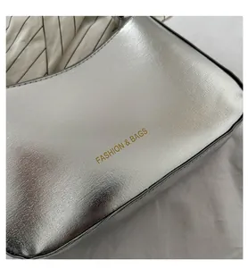 Detail shot of the glossy silver finish and gold lettering on the fashion handbag