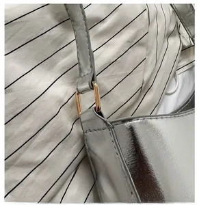 Detail of silver metallic leather bag showing gold-tone ring connector and shoulder strap
