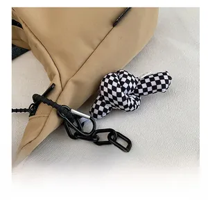Gros plan détaillé d'un pendentif à carreaux noir et blanc sur un sac cabas en toile kaki
