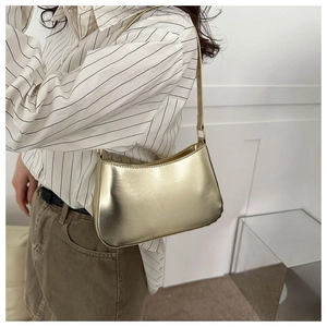 Detail of glossy champagne gold baguette bag with smooth metallic finish and slim strap